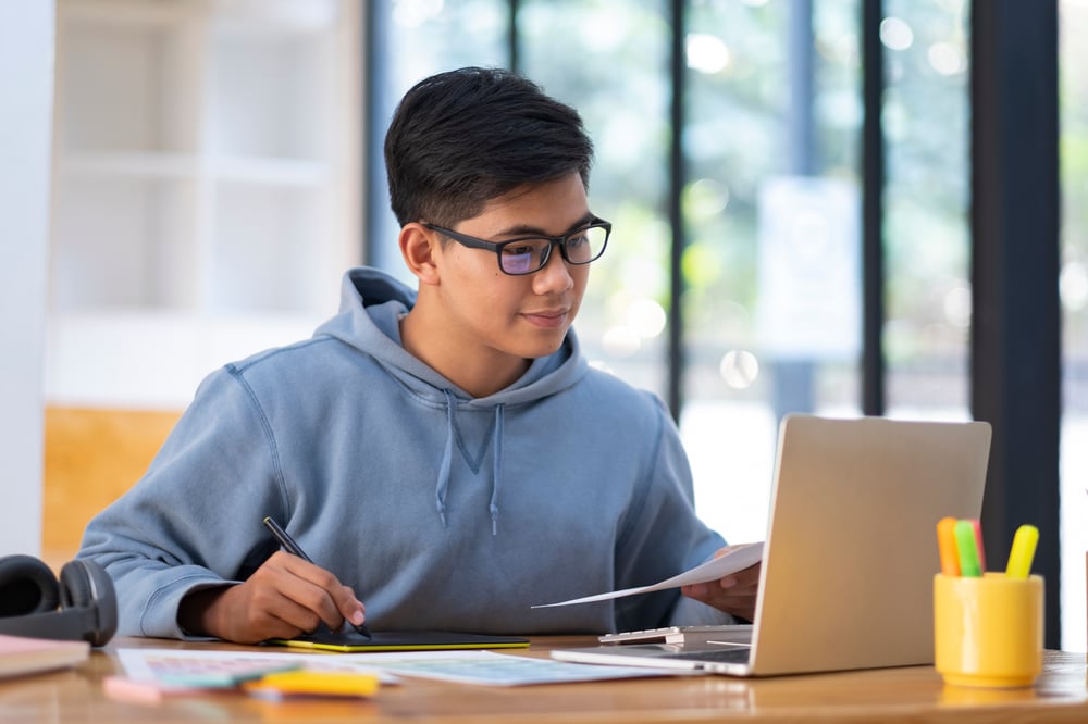 Young collage student using computer and mobile device studying online.